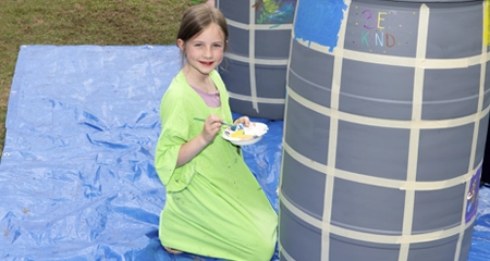 child painting water barrel