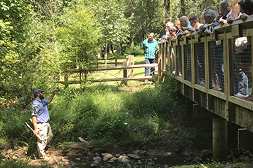 speaker standing on river bank leading conversation about water resource conversation