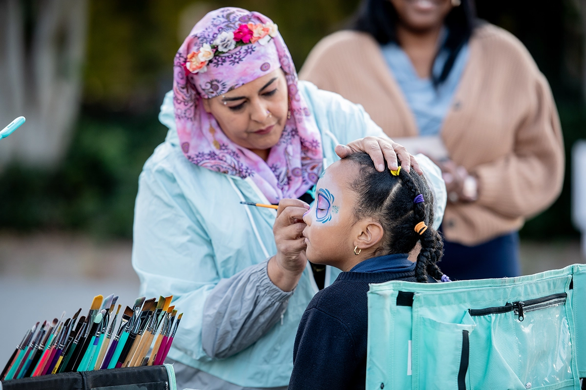 Woman traditionally painting a young girl's face