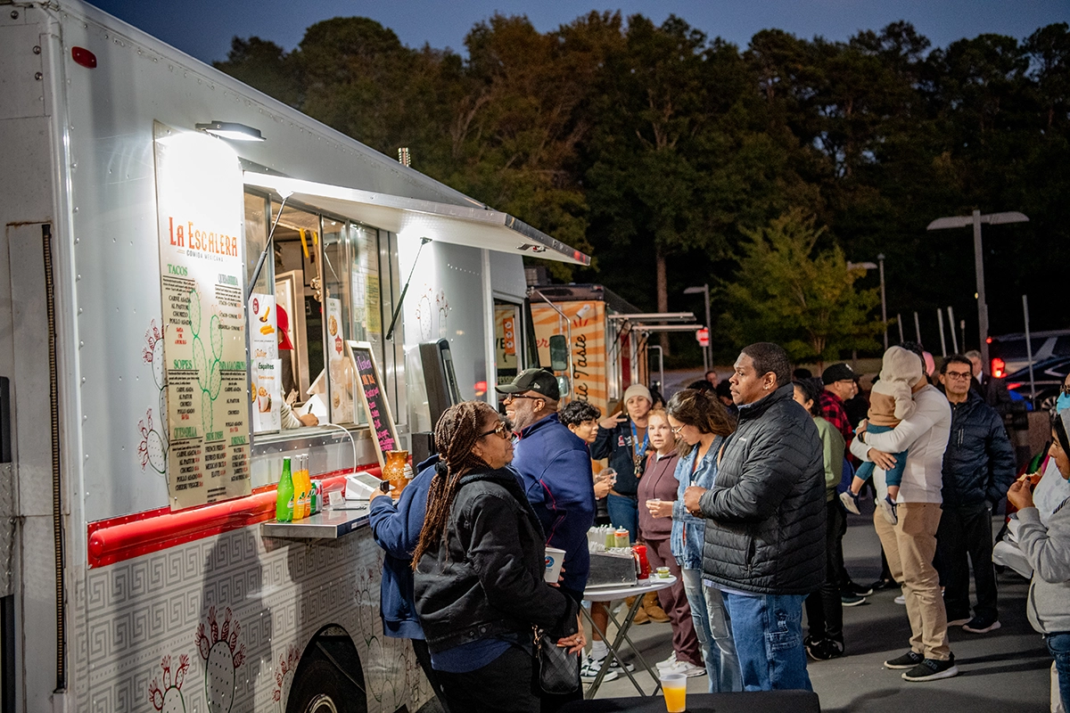 People gathered by the traditional hispanic food trucks