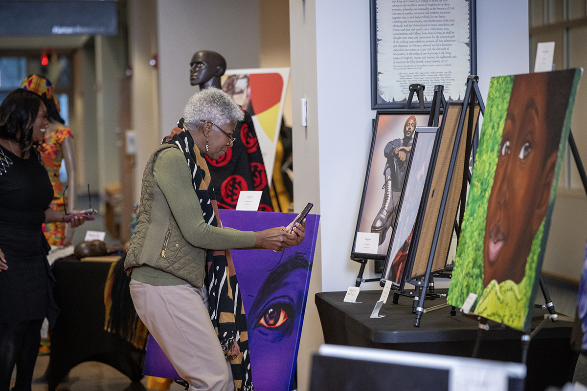 Woman taking photos of the Black History Month art gallery