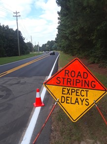 red and yellow sign reading road striping, expect delays